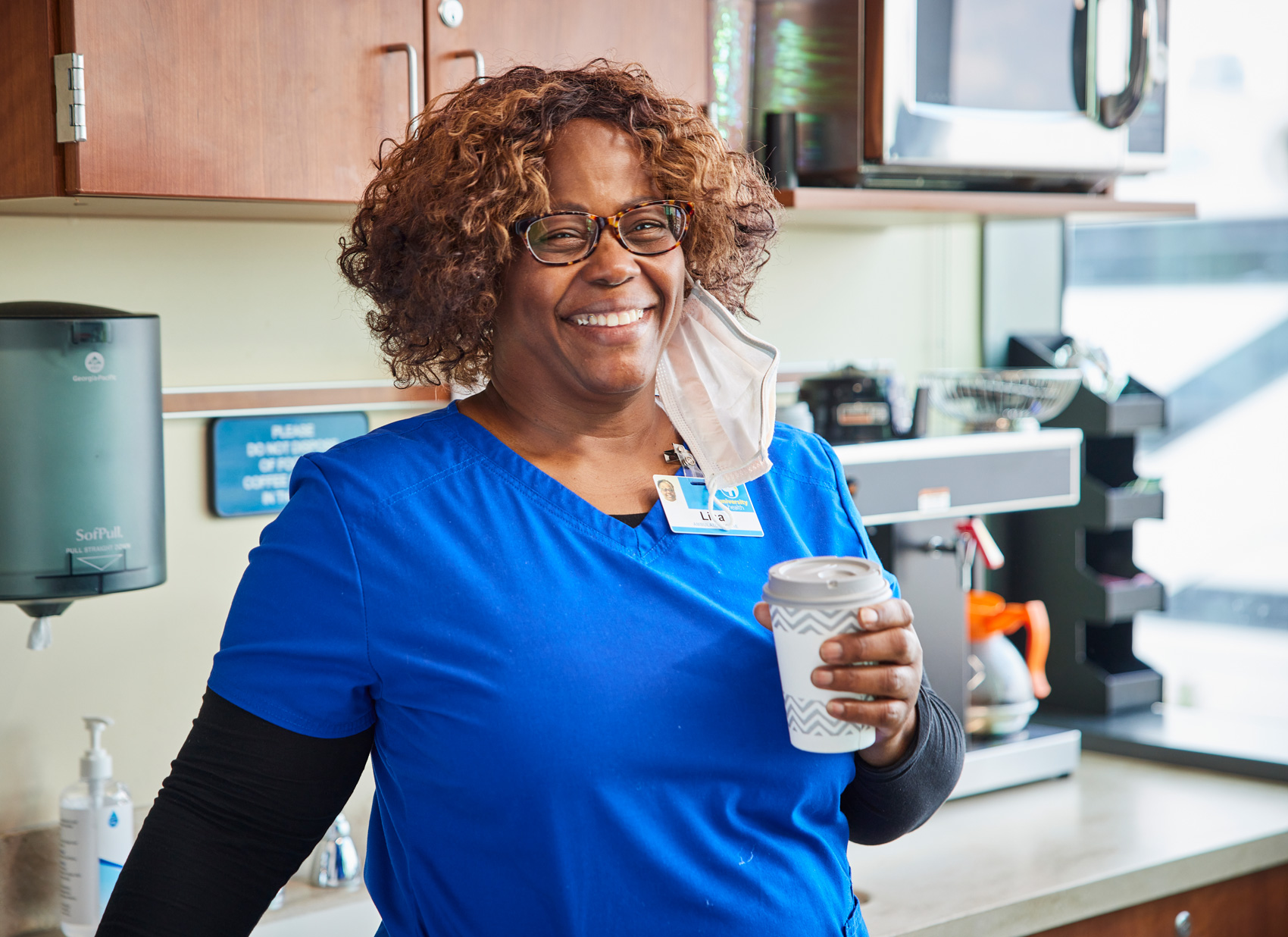 Happy nurse drinking coffee in the breakroom