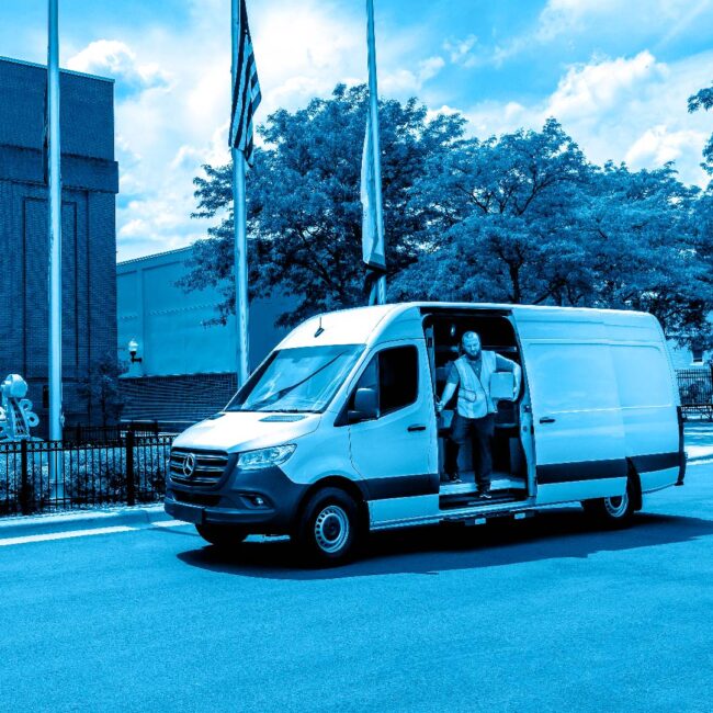 A man exiting a cargo van holding a package