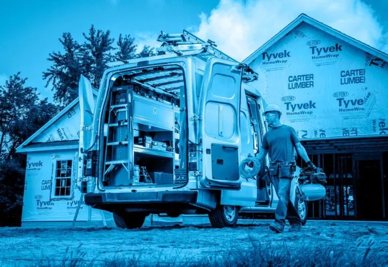 A construction worker approaching the open backdoors of a van with custom shelving