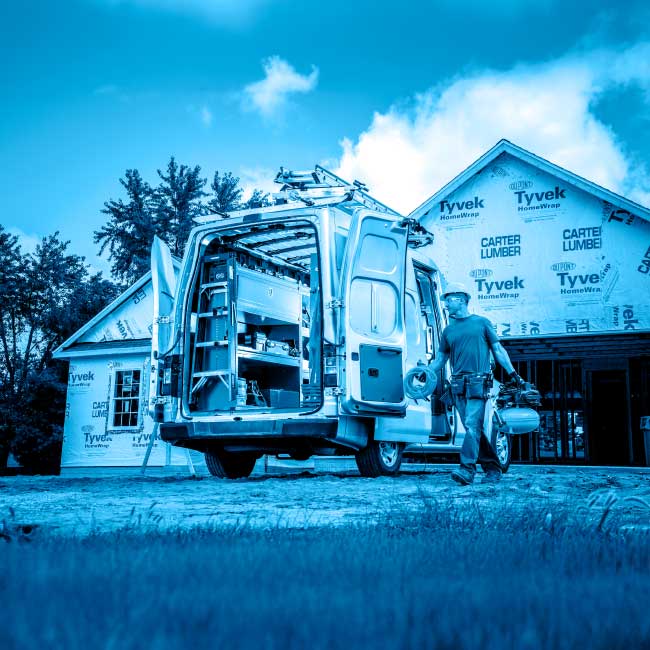 A construction worker approaching the open backdoors of a van with custom shelving