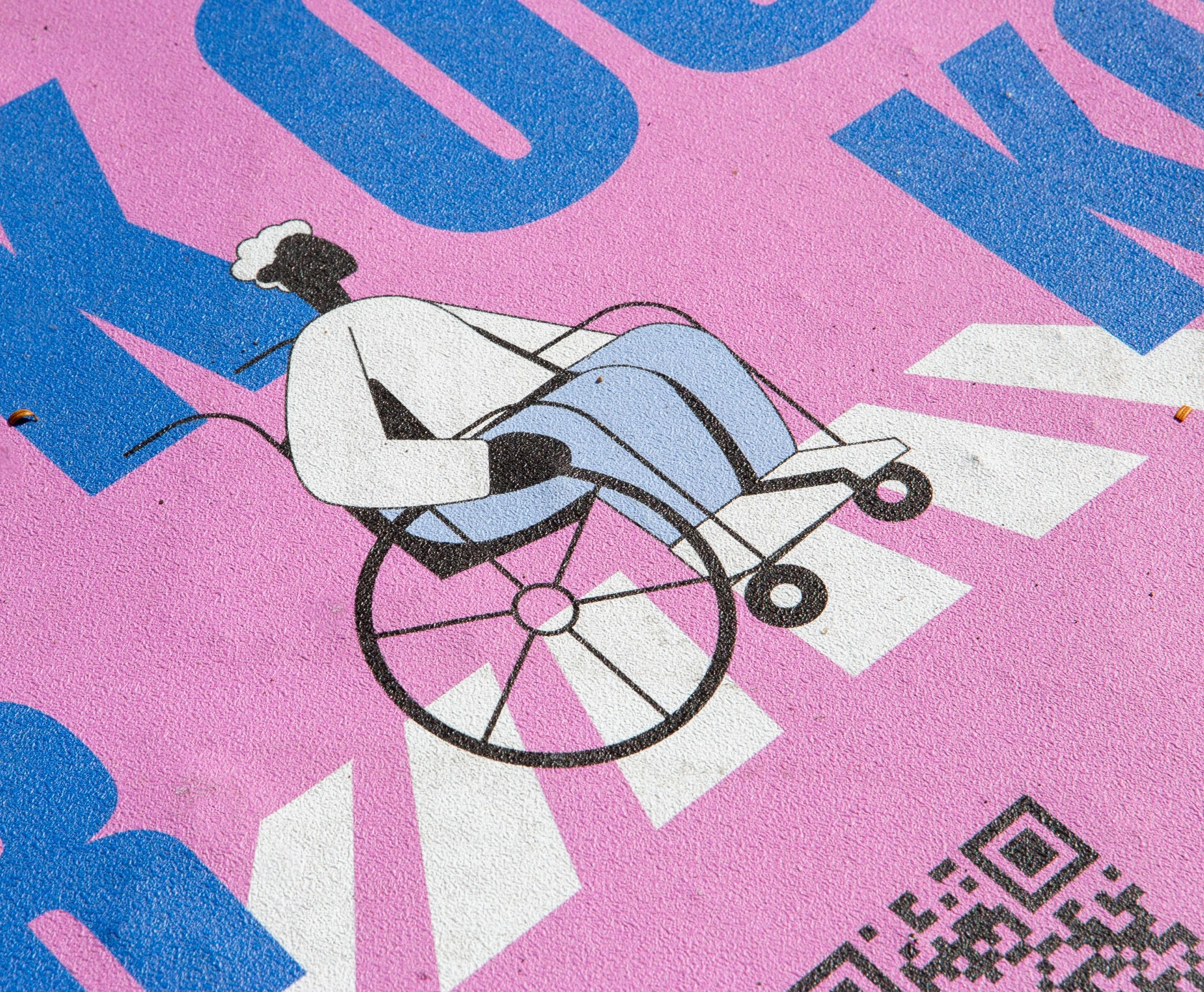 Closeup of sidewalk decal illustration of man in wheelchair in a crosswalk