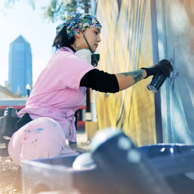 Woman spray painting a mural