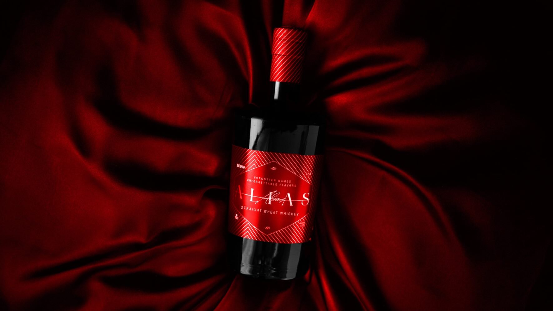Red Alias Whiskey bottle on red silk background